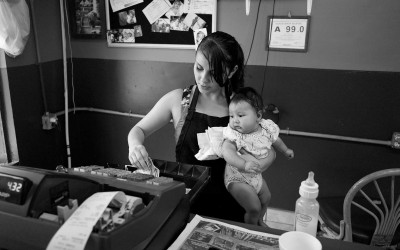 North Carolina September 2011  A young woman holds her niece as she works the cash register at her parents restaurant.