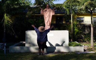 A woman prays to a statue of Jesus out in the yard of Notre Dame d'Haiti in Miami's Little Haiti neighborhood on  a sunny morning on January 3, 2013, a few days after the New Year.  Members of the Catholic church, where masses are given in the Creole language, come often to spend time in the large yard and pray.