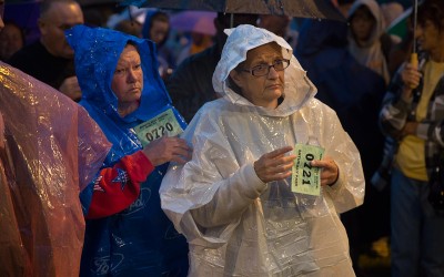 Two women wait for their numbers to be called as they wait before sunrise in the rain with hundreds of other people for free medical care.