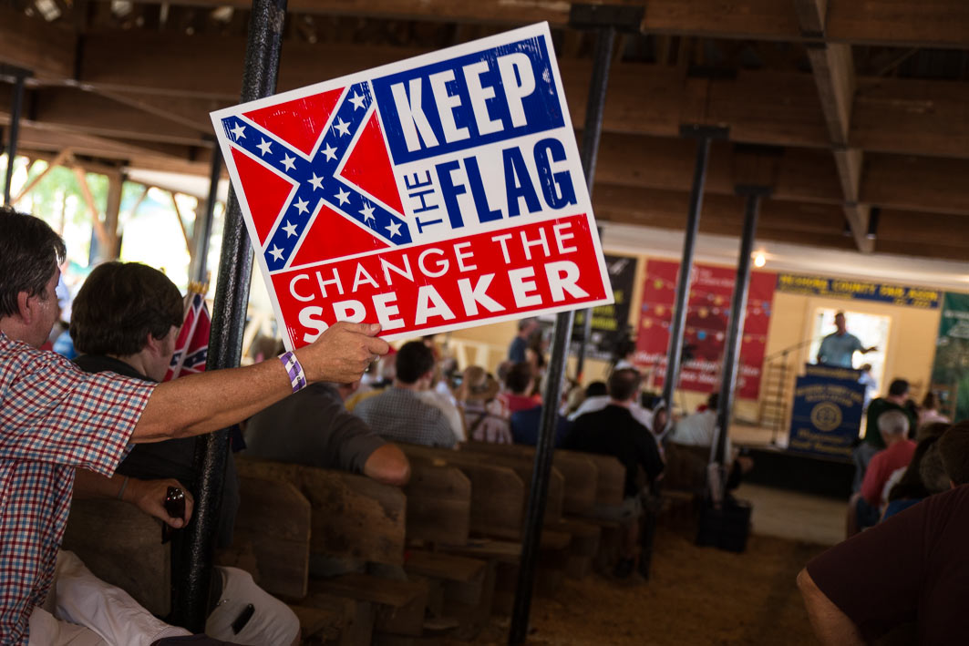 At the Neshoba County Fair   Mississippi House Speaker Philip Gunn speaks as protestors hold up signs calling for his removal because he supported changing the  Mississippi flag.  